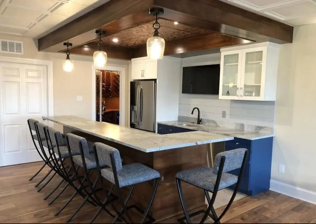 Finished basement with custom bar, quartz counters, wood ceiling detail and pendant lighting by Harlan Custom Contracting