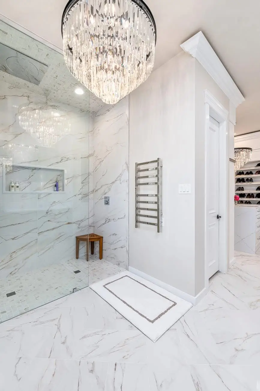 Luxury primary bathroom remodel with marble tile walk-in shower and chandelier by Harlan Custom Contracting