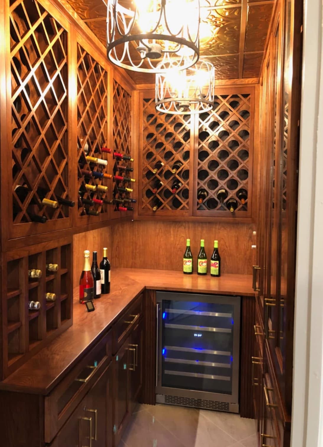 Custom wood wine cellar with lattice racking, counters, and beverage refrigerator